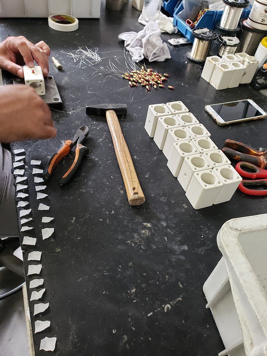 Silver elements, hand tools and ceramic fuse bodies on an assembly bench