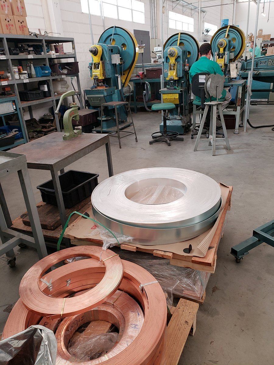 Reels of copper and silver strip stock beside the presses