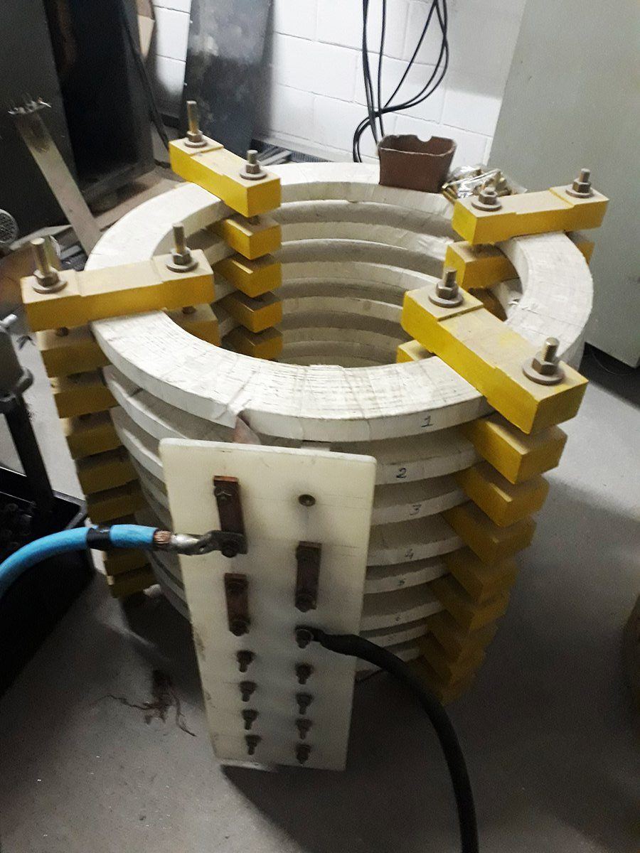 A stack of ceramic fuse bodies clamped in a yellow test jig