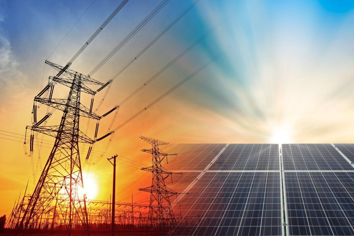 Transmission pylons above a solar array at sunset