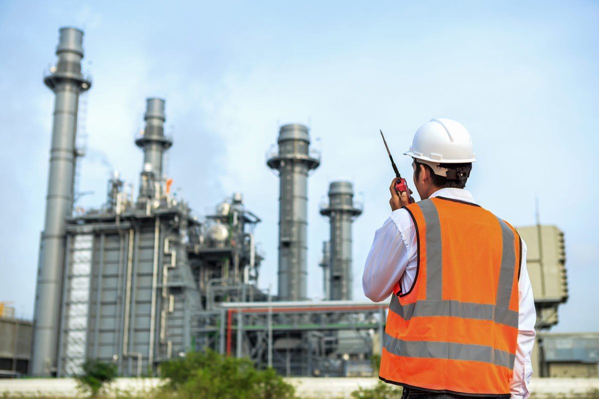 An engineer on radio in front of a power station